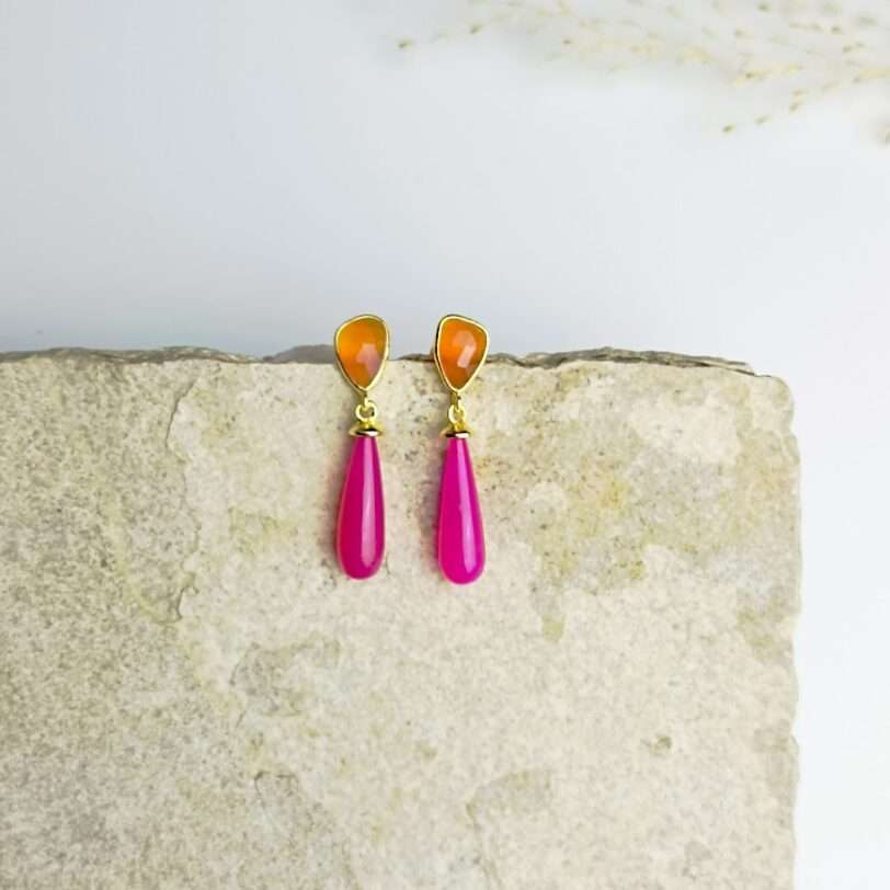 a pair of earrings orange and pink on a rock